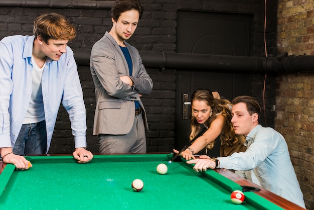 Gratis foto mannelijke vrienden die vrouw het spelen snooker in club bekijken