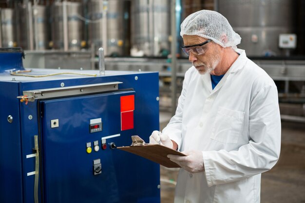 Mannelijke werknemer inspecteren machines in koude drank fabriek