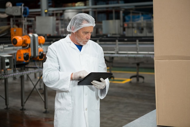 Mannelijke werknemer met behulp van digitale tablet in koude drankfabriek