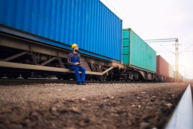 Mannelijke werknemer treintrailers met zeecontainers controleren voor vertrek