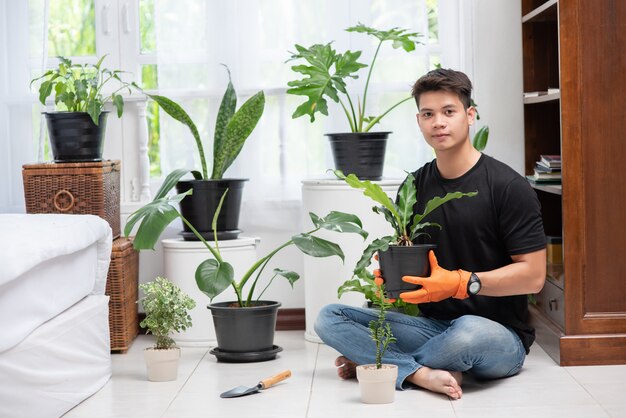 Mannen die oranje handschoenen dragen en bomen binnenshuis planten.