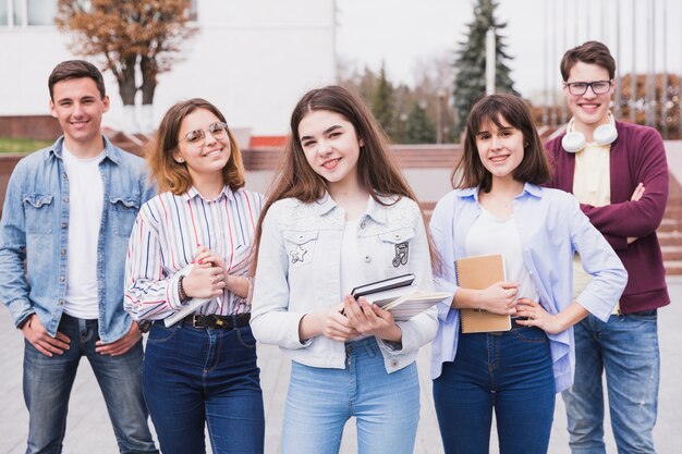 Mannen en vrouwen die zich met boeken bevinden die camera bekijken