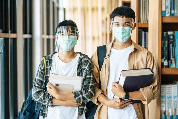 Mannen en vrouwen dragen maskers om boeken te dragen in de bibliotheek.