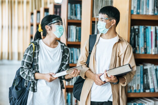 Mannen en vrouwen met maskers staan en lezen in de bibliotheek.