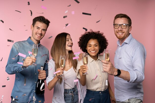 Mannen en vrouwen vieren met champagneglazen en confetti