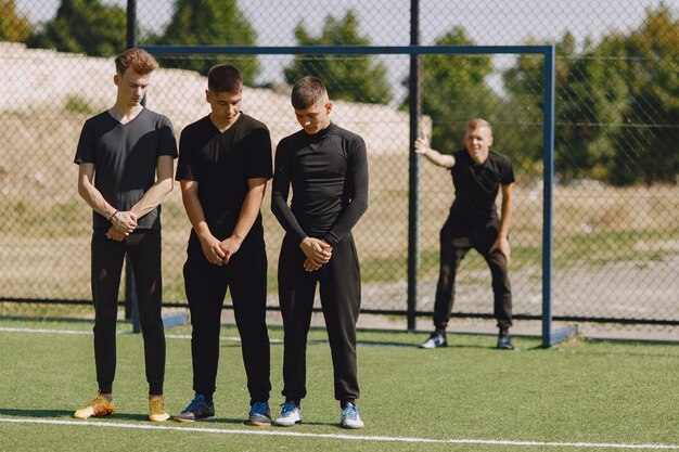 Mannen spelen voetballer in het park. Toernooi op mini-footbal. Kerel in zwarte sportpakken.