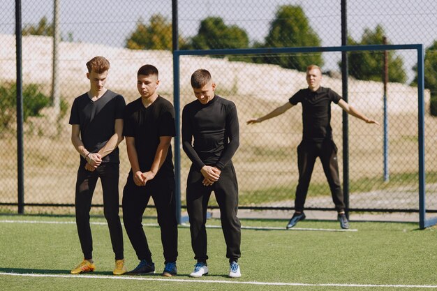 Mannen spelen voetballer in het park. Toernooi op mini-footbal. Kerel in zwarte sportpakken.