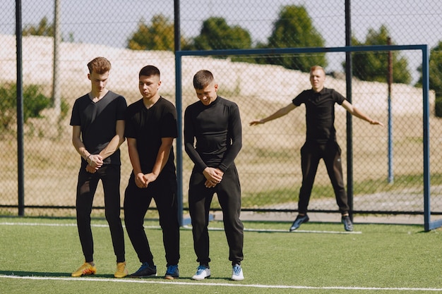 Mannen spelen voetballer in het park. Toernooi op mini-footbal. Kerel in zwarte sportpakken.