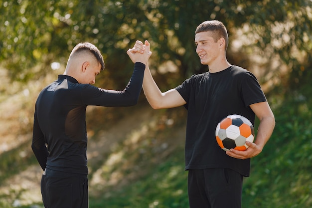 Gratis foto mannen spelen voetballer in het park. toernooi op mini-footbal. kerel in zwarte sportpakken.