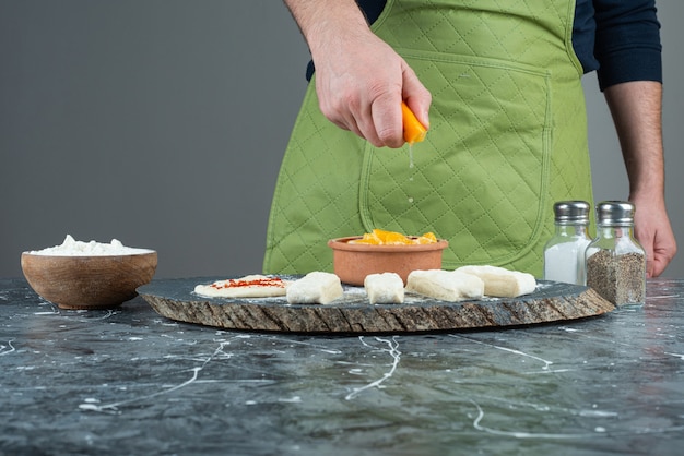 Mannenhand citroensap persen in de garnalen op marmeren tafel.