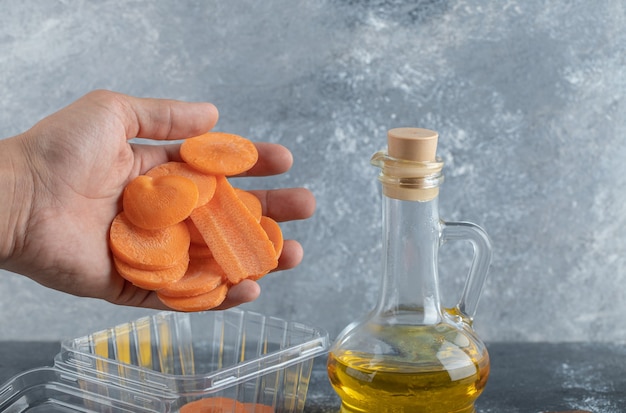 Mannenhand gieten wortelplakken in plastic container.