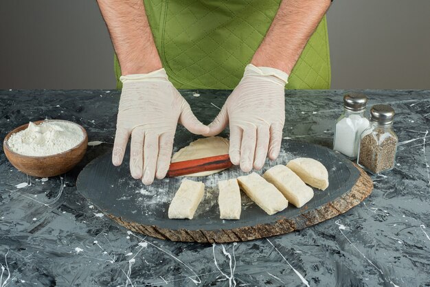 Mannenhand in handschoenen deeg maken op marmeren tafel.