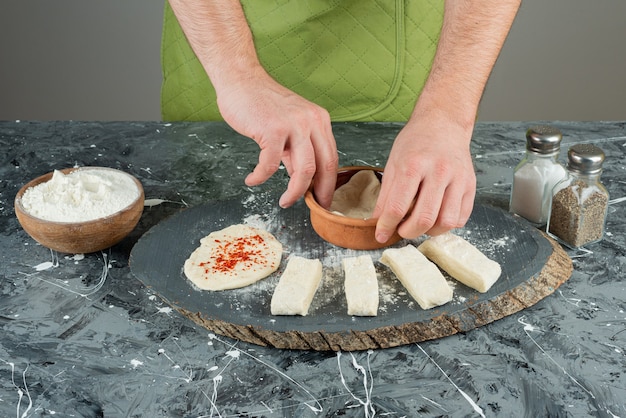 Gratis foto mannenhand in handschoenen deeg maken op marmeren tafel.