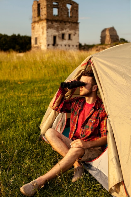 Mannetje die in het kamperen tent binoculair kijken