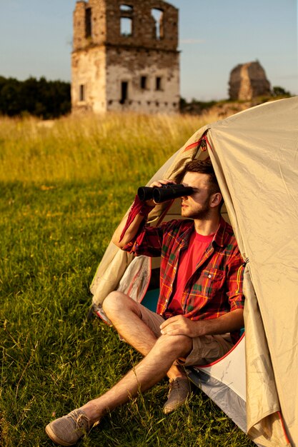 Mannetje die in het kamperen tent binoculair kijken