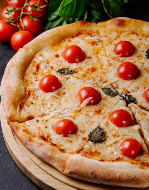 Gratis foto margarita-pizza met cherrytomaten en basilicumbladeren.