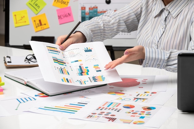 Marketing zakendame in gestreept shirt op kantoor met computer die verschillende grafieken uitlegt