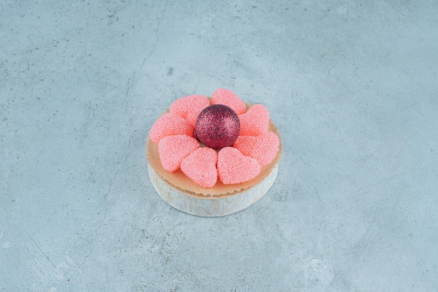 Marmelade ring rond een kerstbal op een stuk hout op blauw.