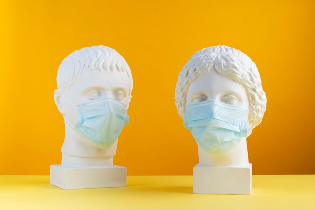 Marmeren sculpturen van historische figuren met medische maskers