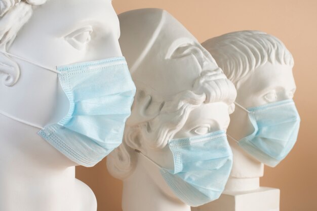 Marmeren sculpturen van historische figuren met medische maskers