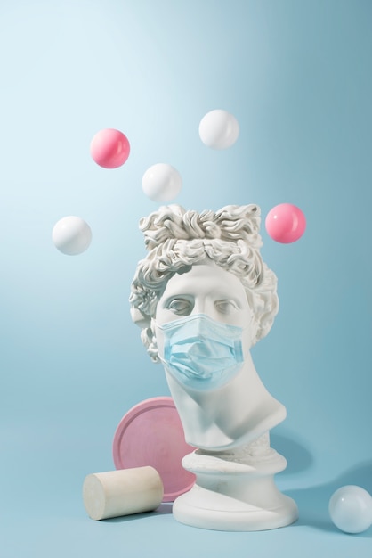 Gratis foto marmeren sculptuur van historische figuur met medisch masker en ballen