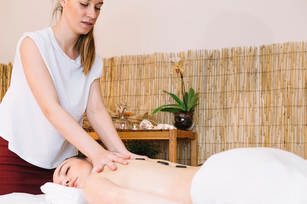 Massageconcept met stenen op de rug van de vrouw