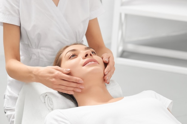 Massagehand voor jonge glimlachende vrouw in de schoonheidssalon