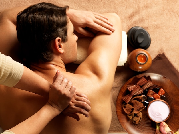 Masseur doet massage van ruggengraat op het lichaam van de man in de spa salon. Schoonheidsbehandeling concept.