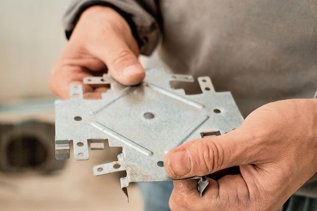 Gratis foto master houdt in zijn handen een structureel metalen profiel voor de installatie van een gipsplaten plafondframe, close-up, selectieve scherpstelling. industriële renovatie en renovatie