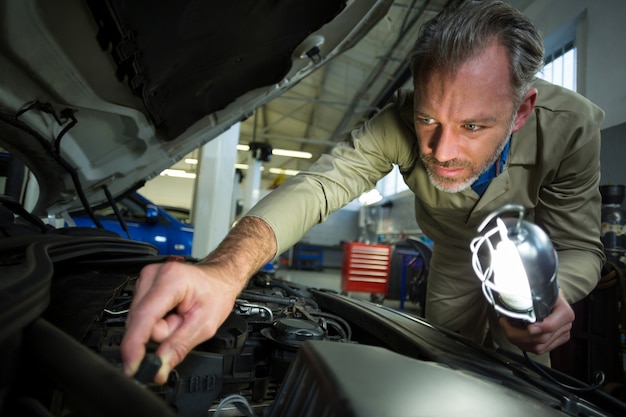 Mechanic de behandeling van een auto met een lamp