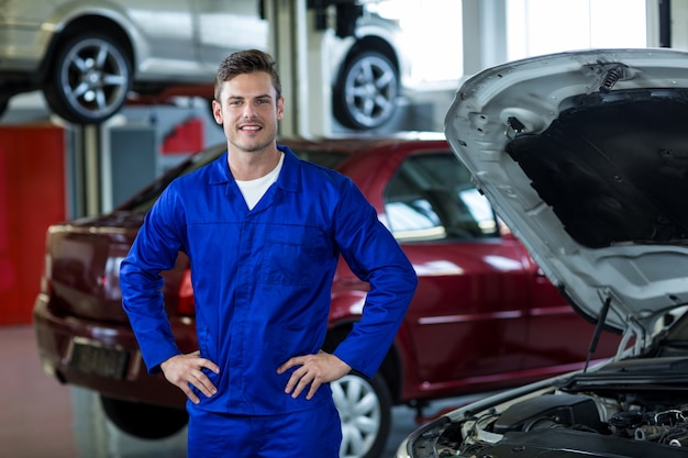 Mechanic staande met de handen op de heup in reparatiewerkplaats