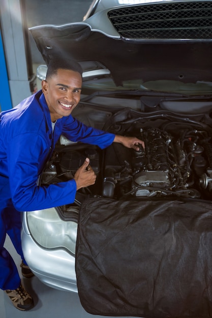 Gratis foto mechanic zien thumbs up tijdens het repareren van auto