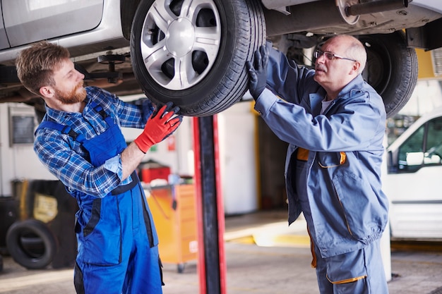 Gratis foto mechanica die een auto in de werkplaats herstelt