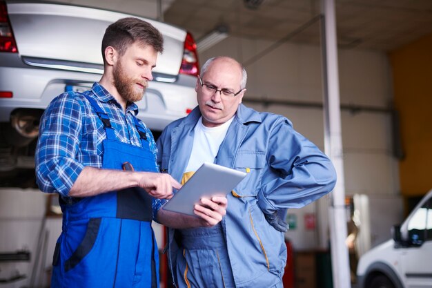 Mechanica die een auto in de werkplaats herstelt