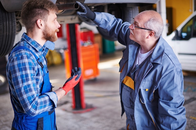 Gratis foto mechanica die een auto in de werkplaats herstelt