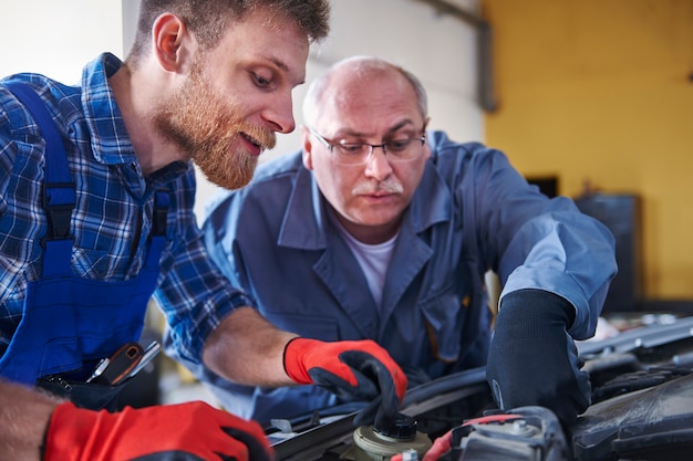 Mechanica die een auto in de werkplaats herstelt