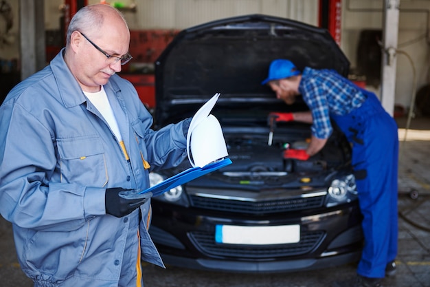 Mechanica die een auto in de werkplaats herstelt