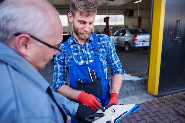 Gratis foto mechanica die een planning in een werkplaats controleert