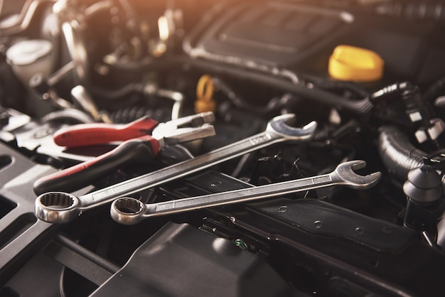 Mechanische hand controleren en repareren van een kapotte auto in de garage van de auto-service.