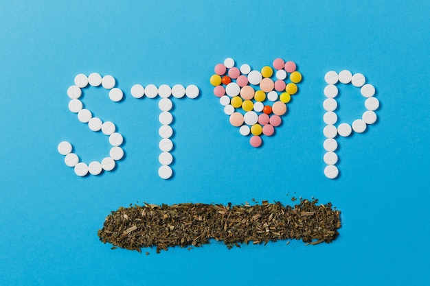 Medicatie witte, kleurrijke ronde tabletten in woord stop geïsoleerd op blauwe achtergrond Gratis Foto