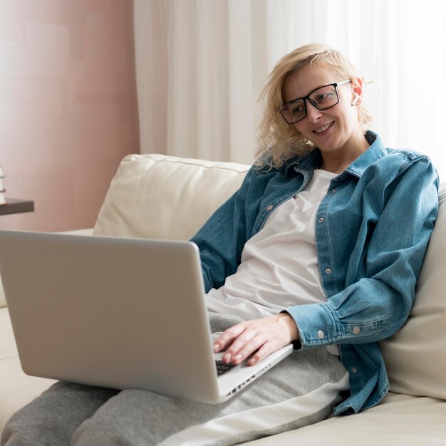 Medio geschotene blonde vrouwenzitting op laag en het werken aan laptop