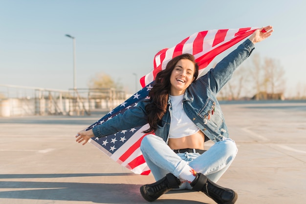 Medio geschotene jonge vrouw die het grote gekruiste been van de de vlagzitting van de VS houdt