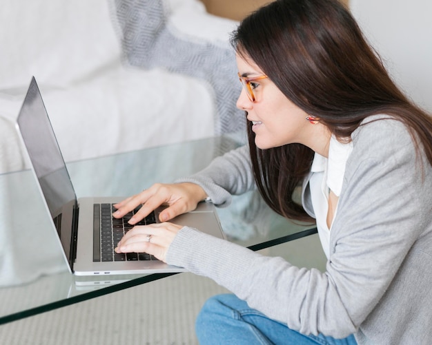 Medio geschotene vrouw die aan laptop bij glaslijst werkt