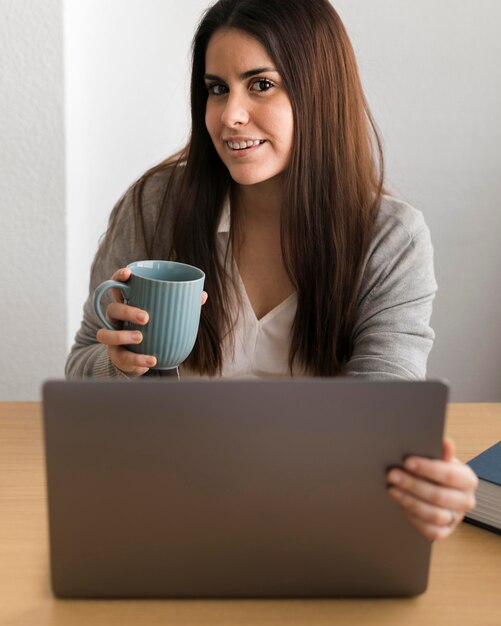 Medio geschotene vrouw die aan laptop werkt en koffie drinkt