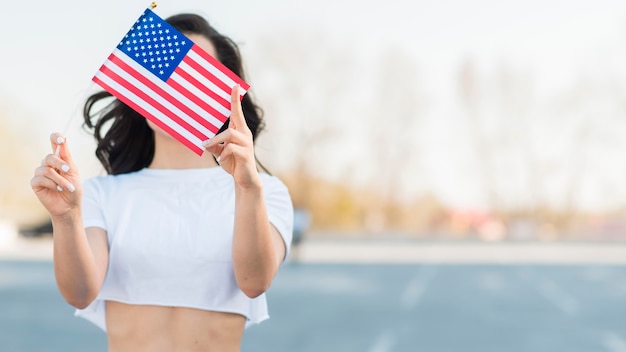 Medio geschotene vrouw die de vlag van de vs over gezicht houdt