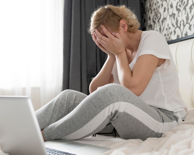 Medio geschotene vrouw die haar hoofd in handen houdt