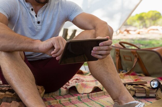 Medio sectie van de mens die tablet in tent gebruiken