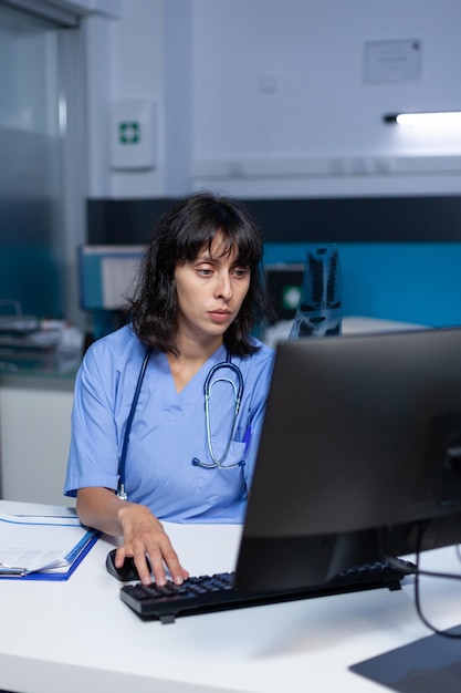 Medisch assistent met röntgenscan voor onderzoek en diagnose na uren. verpleegkundige die radiografieresultaten bekijkt voor gezondheidszorg en medisch advies, 's avonds laat aan het werk in de kast.