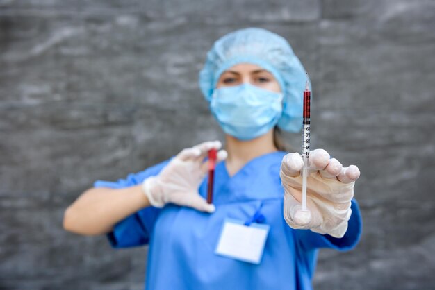 Medisch werker die rode reageerbuis vasthoudt en ernaar kijkt in het laboratorium