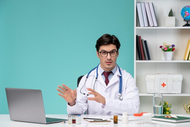 Medische jonge slimme arts in laboratoriumjas die op afstand op computer werkt en aan de patiënt uitlegt